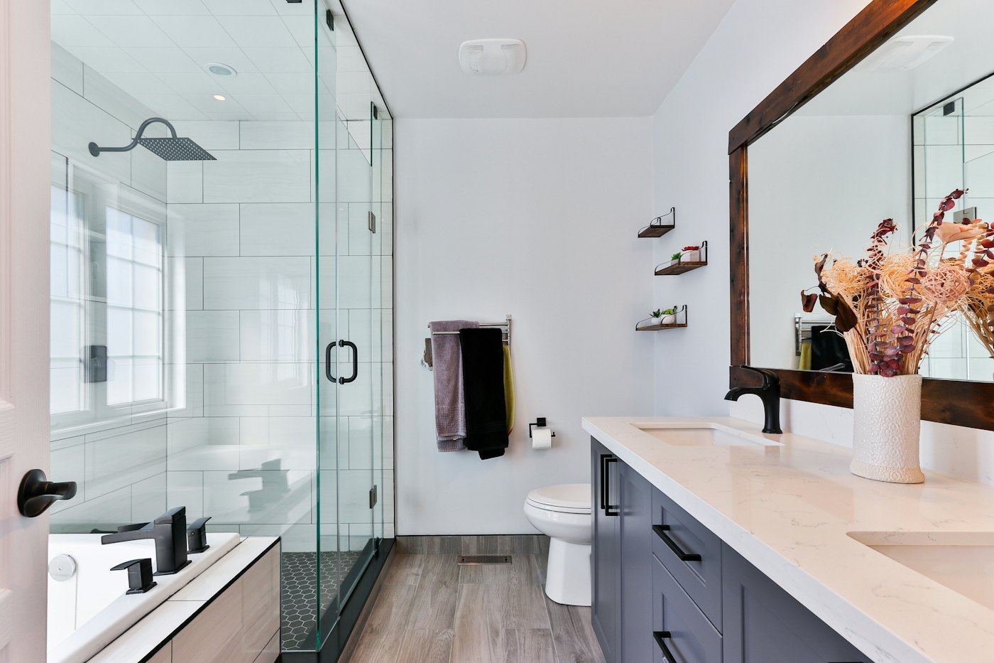 Remodeled bathroom with a glass shower, white wall tile, vanity, and toilet.