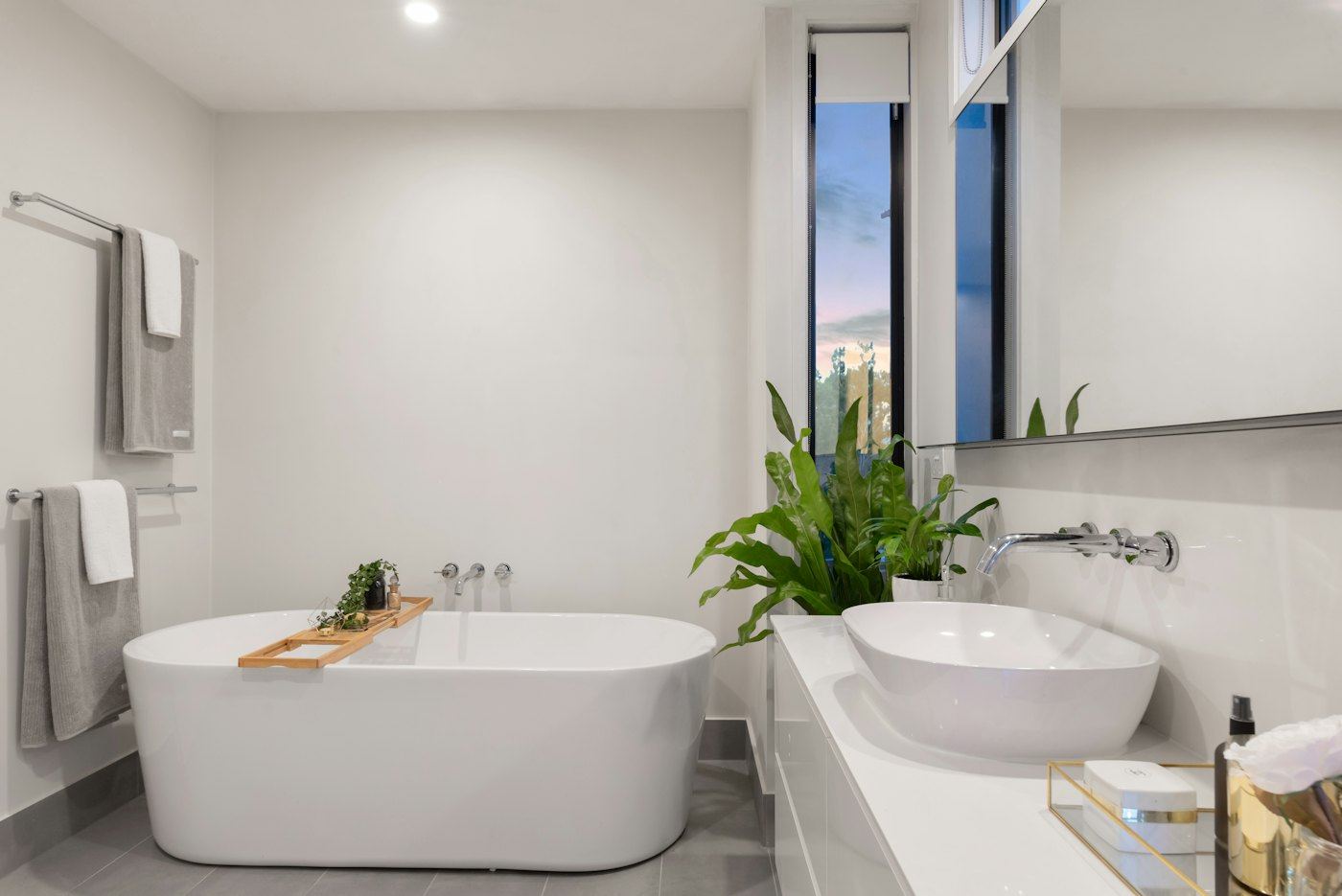 Bathroom with a freestanding tub, wall-mounted sink, and gray floor tile.