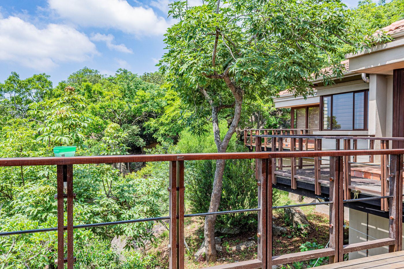 Wood deck and railing on the side of a house, looking out over trees.