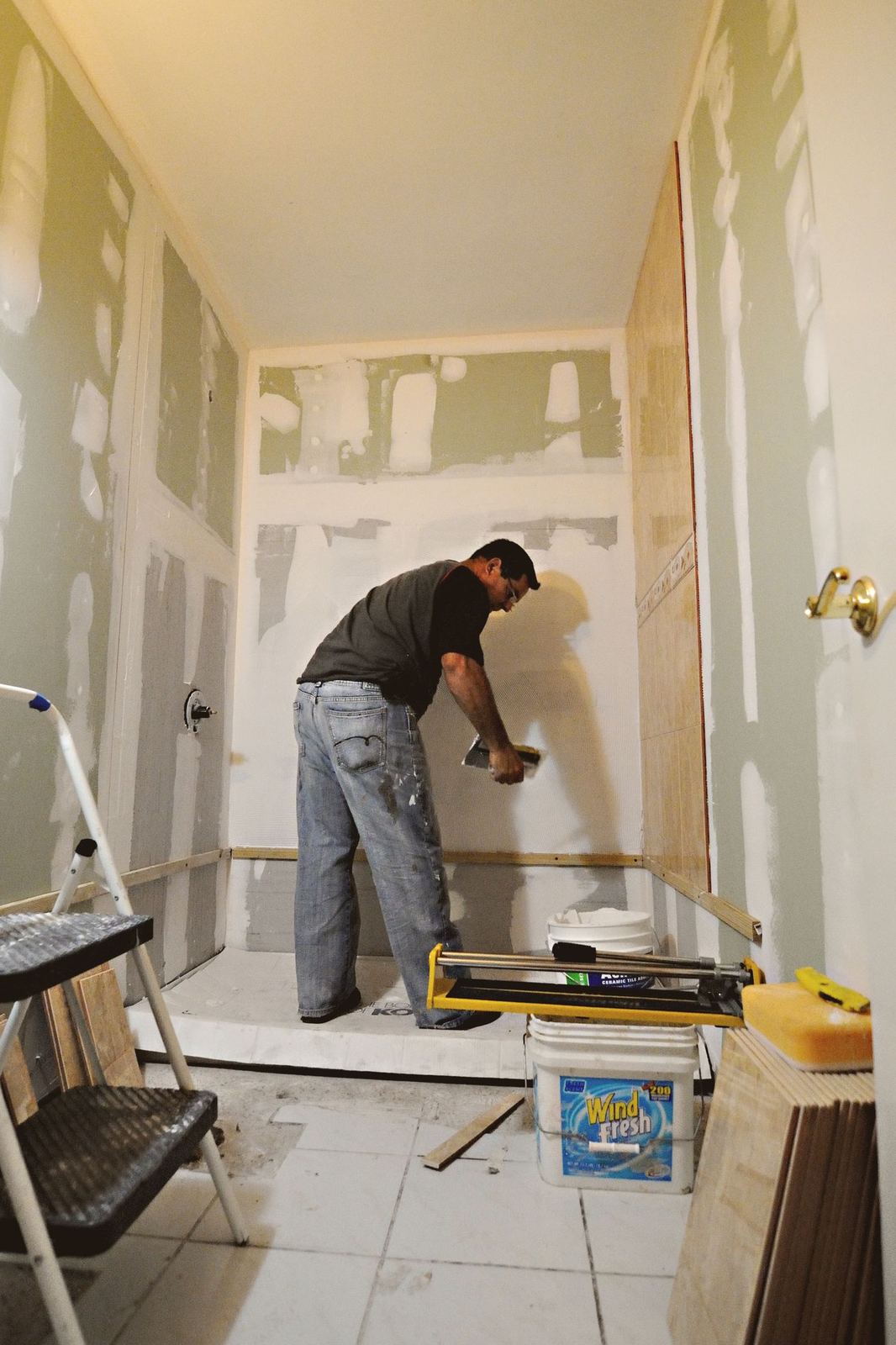 Worker finishing drywall with joint compound in a small room during a remodel.