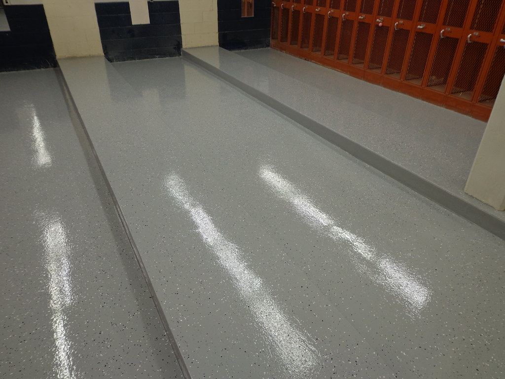 Glossy gray epoxy floor with fine color flakes beside a row of lockers.