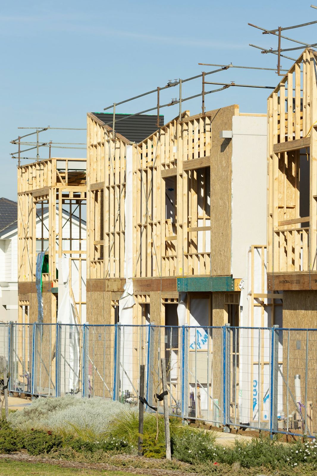 Row of houses under construction with wood framing and sheathing still exposed.