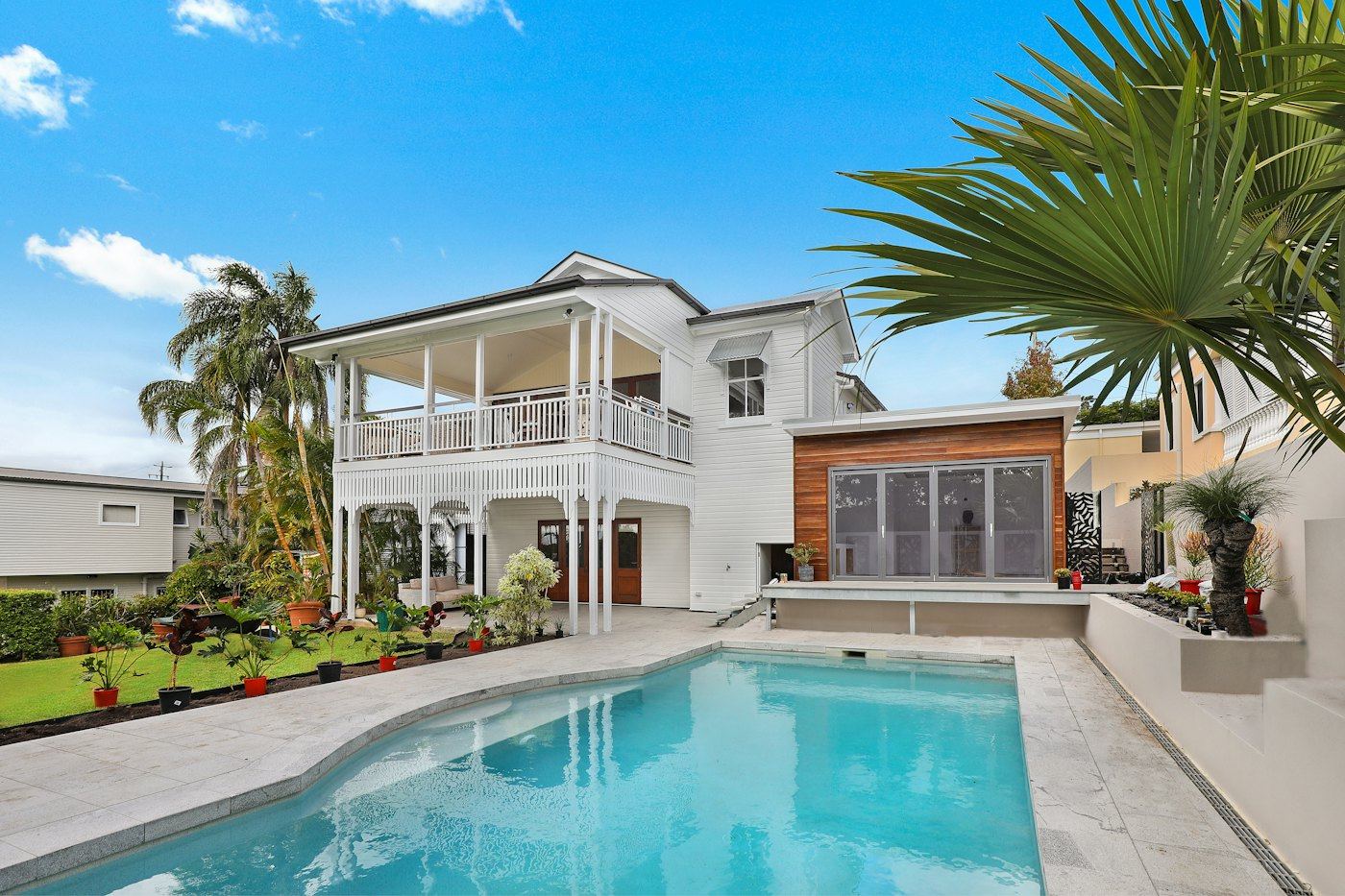 House with a covered upper porch, white railings, and posts over a patio.