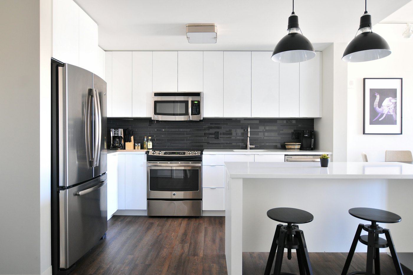 Kitchen with a dark subway-tile backsplash, white cabinets, and wood-look flooring.